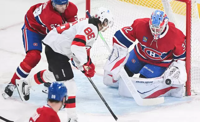 Montreal Canadiens' Noah Dobson (53) defends against New Jersey Devils' Jack Hughes (86) as he moves in on Canadiens goaltender Jacob Fowler (32) during first period of an NHL hockey game in Montreal, Sunday, April 5, 2026.(Graham Hughes/The Canadian Press via AP)