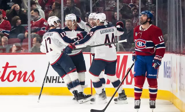 Columbus Blue Jackets' Mason Marchment (17), Danton Heinen, second from left, Erik Gudbranson (44) and Charlie Coyle (3) celebrate after a goal while Montreal Canadiens' Alex Newhook (15) looks on during first-period NHL hockey game action in Montreal, Saturday, April 11, 2026. (Christopher Katsarov/The Canadian Press via AP)