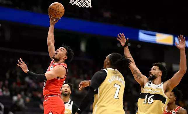 Chicago Bulls guard Tre Jones, left, goes to the basket past Washington Wizards guard Bub Carrington (7) and forward Anthony Gill (16) during the first half of an NBA basketball game, Thursday, April 9, 2026, in Washington. (AP Photo/Nick Wass)