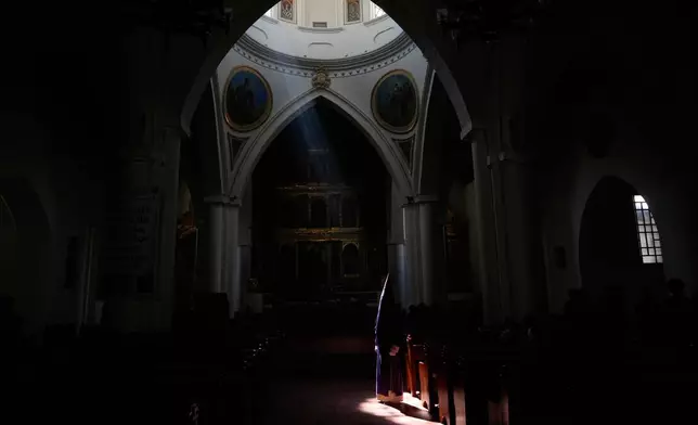 A hooded penitent from the Nazareno brotherhood waits for the Good Friday procession inside the Cathedral Basilica of St. James the Apostle during Holy Week in Tunja, Colombia, Friday, April 3, 2026. (AP Photo/Fernando Vergara)
