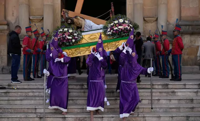Penitents from the Nazareno brotherhood carry a statue of Jesus down the steps of the Cathedral Basilica of St. James the Apostle for a Good Friday procession during Holy Week in Tunja, Colombia, Friday, April 3, 2026. (AP Photo/Fernando Vergara)