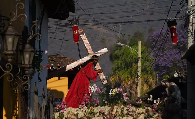 A statue of Jesus Christ with a cross makes its way past electric cables at La Merced church's Good Friday procession during Holy Week in Antigua, Guatemala, Friday, April 3, 2026. (AP Photo/Moises Castillo)