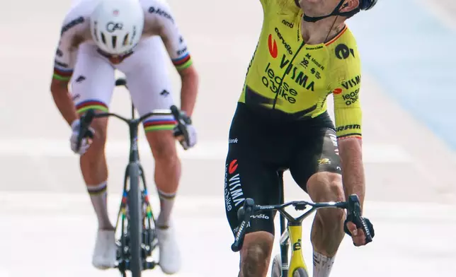 Belgium's Wout van Aert crosses the finish line ahead of Tadej Pogacar of Slovenia, left, to win the Paris-Roubaix cycling race in Roubaix, France, Sunday, April 12, 2026. Van Aert pointed his finger skywards to commemorate Belgian cyclist Michael Goolaerts who died after crashing in the race in 2018. (AP Photo/Jean-Francois Badias)