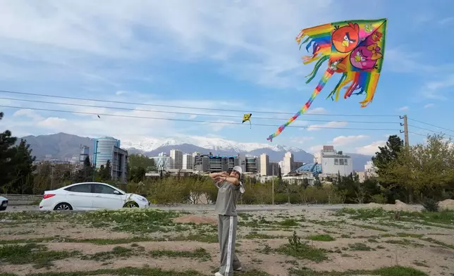 A woman flies a kite as she enjoys her weekend at Pardisan park in Tehran, Iran, Friday, April 10, 2026. (AP Photo/Vahid Salemi)