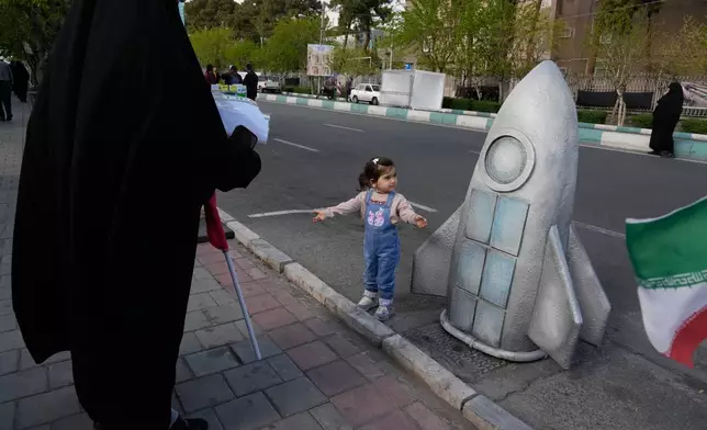 A girl stands next to replica of a space craft in a memorial for school children who were killed during a strike on a school in southern town of Minab on Feb. 28, in downtown Tehran, Iran, Tuesday, April 7, 2026. (AP Photo/Vahid Salemi)