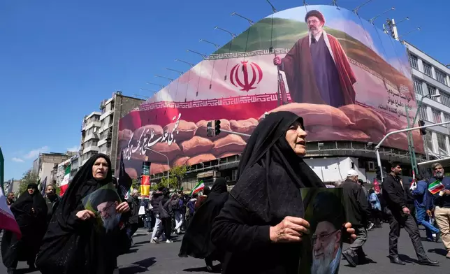 Women walk past a billboard depicting Iran's Supreme Leader Mojtaba Khamenei as government supporters gather to mark the 40th day since the killing of his father, slain Supreme Leader Ayatollah Ali Khamenei, in Tehran, Iran, Thursday, April 9, 2026. (AP Photo/Vahid Salemi)