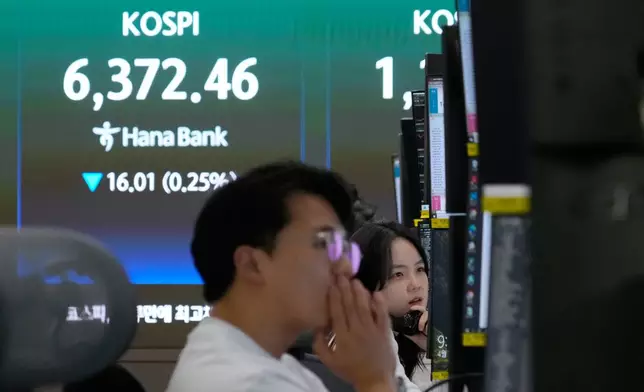 A currency trader talks on the phone near a screen showing the Korea Composite Stock Price Index (KOSPI) at the foreign exchange dealing room of the Hana Bank headquarters in Seoul, South Korea, Wednesday, April 22, 2026. (AP Photo/Ahn Young-joon)