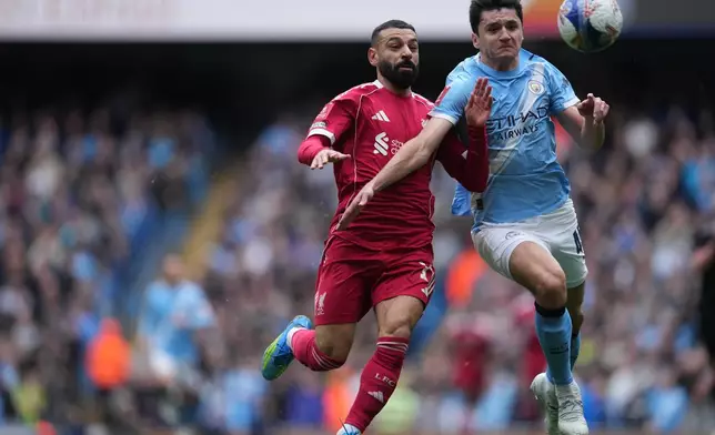 Liverpool's Mohamed Salah;, left, and Manchester City's Abdukodir Khusanov fight for the ball during the FA Cup quarter-final soccer match between Manchester City and Liverpool in Manchester, England, Saturday, April 4, 2026. (AP Photo/Jon Super)