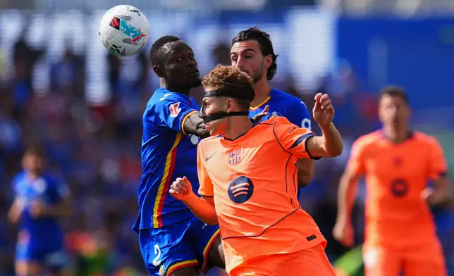 Barcelona's Fermin Lopez, front, is challenged by Getafe's Djene Dakonam during the Spanish La Liga soccer match between Getafe and Barcelona in Getafe, Spain, Saturday, April 25, 2026. (AP Photo/Manu Fernandez)