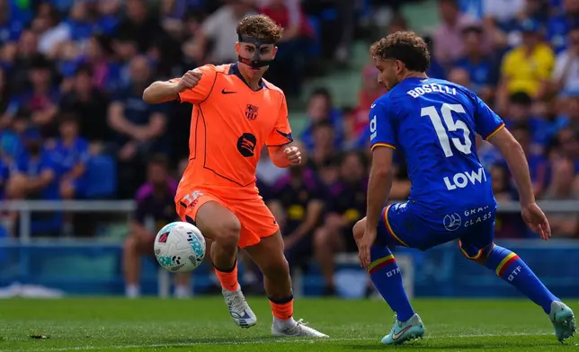 Barcelona's Fermin Lopez, left, and Getafe's Sebastian Boselli compete for the ball during the Spanish La Liga soccer match between Getafe and Barcelona in Getafe, Spain, Saturday, April 25, 2026. (AP Photo/Manu Fernandez)