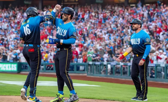 Philadelphia Phillies' Brandon Marsh, left, celebrates after his three-run home run with Bryce Harper, center, and Kyle Schwarber, right, during the first inning of a baseball game against the Arizona Diamondbacks, Friday, April 10, 2026, in Philadelphia. (AP Photo/Chris Szagola)