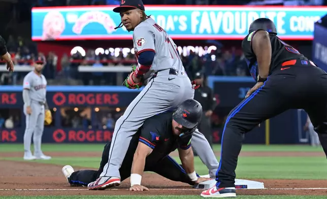 Toronto Blue Jays' Davis Schneider (bottom) slides safely into third base ahead of a tag by Cleveland Guardians third baseman Jose Ramirez (11) in first inning of a baseball game in Toronto on Friday, April 24, 2026. (Jon Blacker/The Canadian Press via AP)
