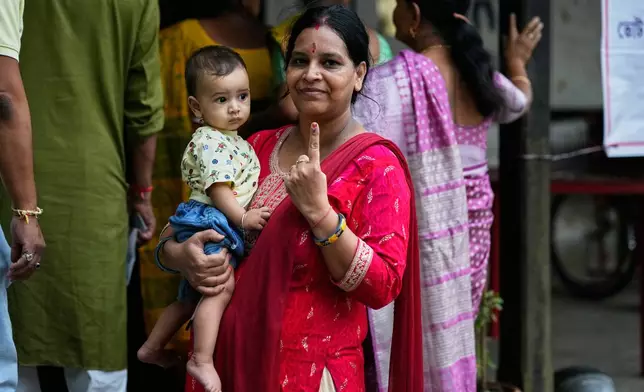 A woman shows the indelible ink mark on her index finger after casting her vote at a polling center during the state election in Guwahati, India, Thursday, April 9, 2026. (AP Photo/Anupam Nath)
