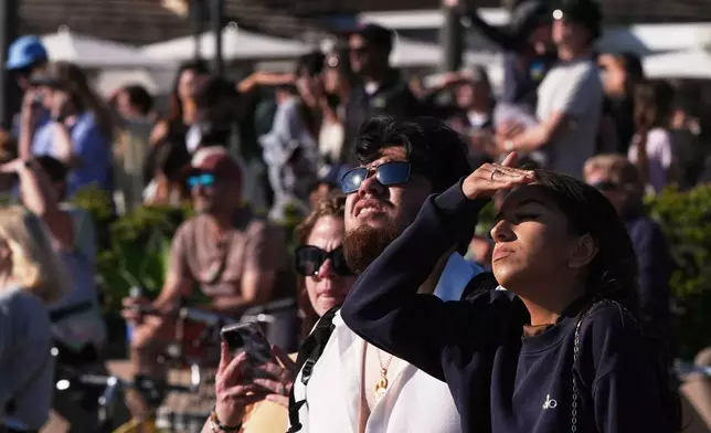 People wait for a glimpse of the return of NASA's Artemis II Friday, April 10, 2026, along the beach in Coronado, Calif. (AP Photo/Gregory Bull)