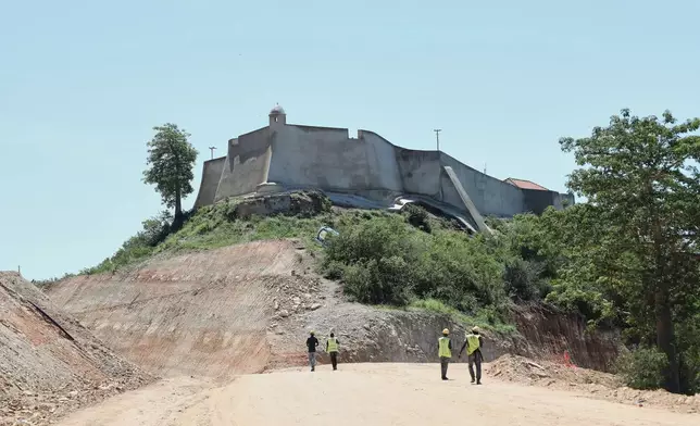 Workers walk by the 16th century fortress in Muxima, Angola, Saturday, April 11, 2026. (AP Photo)
