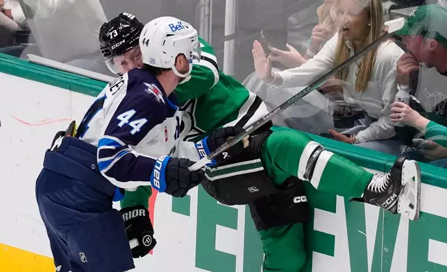 Winnipeg Jets defenseman Josh Morrissey (44) slams Dallas Stars left wing Adam Erne (73) against the boards in the second period of an NHL hockey game Thursday, April 2, 2026, in Dallas. (AP Photo/Tony Gutierrez)