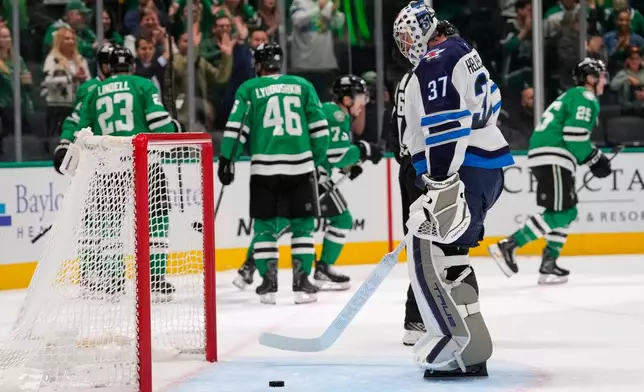 Winnipeg Jets goaltender Connor Hellebuyck (37) looks down at the ice as the Dallas Stars celebratge a goal by Arttu Hyry in the first period of an NHL hockey game Thursday, April 2, 2026, in Dallas. (AP Photo/Tony Gutierrez)