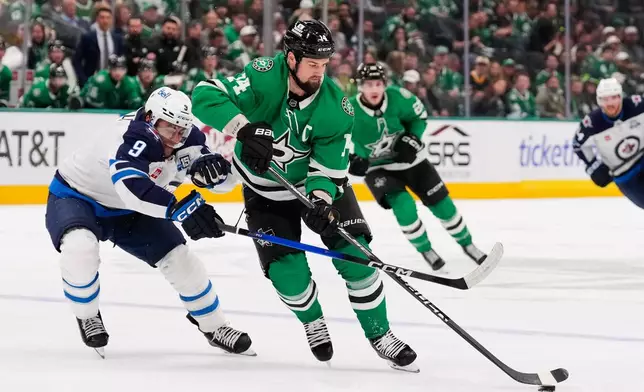 Dallas Stars left wing Jamie Benn (14) takes control of the puck in front of Winnipeg Jets' Alex Iafallo (9) in the first period of an NHL hockey game Thursday, April 2, 2026, in Dallas. (AP Photo/Tony Gutierrez)