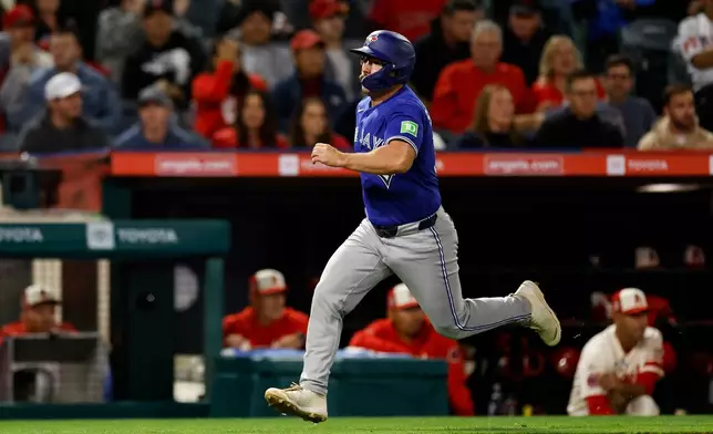 Toronto Blue Jays' Davis Schneider (36) runs to home plate to score off a single hit by Toronto Blue Jays designated hitter Eloy Jimenez (74) during the eighth inning of a baseball game against the Los Angeles Angels, Tuesday, April 21, 2026, in Anaheim, Calif. (AP Photo/Caroline Brehman)