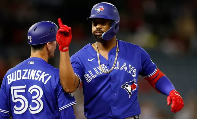 Toronto Blue Jays designated hitter Eloy Jiménez (74) reacts after a single that scored Davis Schneider (36) during the eighth inning of a baseball game Tuesday, April 21, 2026, in Anaheim, Calif. (AP Photo/Caroline Brehman)