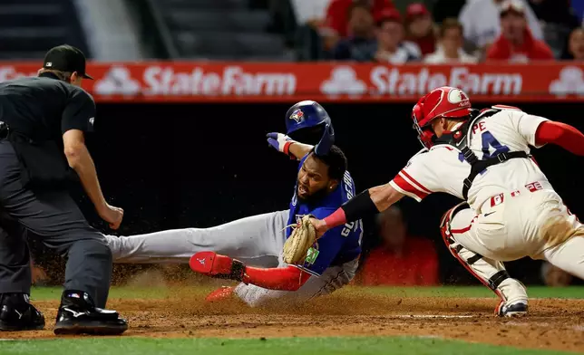 Toronto Blue Jays' Vladimir Guerrero Jr. slides into home plate as Los Angeles Angels catcher Logan O'Hoppe (14) attempts to tag him out after Blue Jays' Lenyn Sosa doubled to right field, driving in Guerrero and Ernie Clement during the eighth inning of a baseball game Tuesday, April 21, 2026, in Anaheim, Calif. (AP Photo/Caroline Brehman)