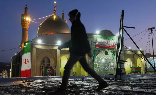 A youngster walks past a religious complex that Iranian officials say was hit by an airstrike in Zanjan, Iran, Saturday, April 4, 2026. (AP Photo/Francisco Seco)