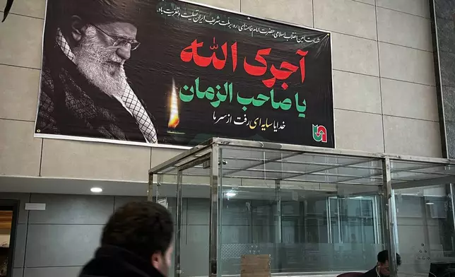 Under a poster of Iran's slain Supreme Leader Ayatollah Ali Khamenei, Iranian border police check passports at a border crossing between Turkey and Iran in Razi, Iran, Saturday, April 4, 2026.. (AP Photo/Francisco Seco)