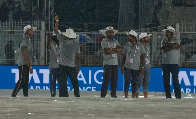 Ground staff stand on rain covers as it rains during the Indian Premier League cricket match between Kolkata Knight Riders and Punjab Kings in Kolkata , India, Monday, April 6, 2026. (AP Photo/Bikas Das)