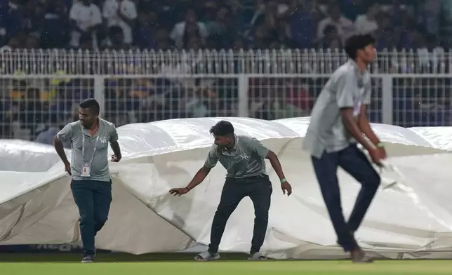 Ground staff pull in rain covers to the field as it rains during the Indian Premier League cricket match between Kolkata Knight Riders and Punjab Kings in Kolkata , India, Monday, April 6, 2026. (AP Photo/Bikas Das)