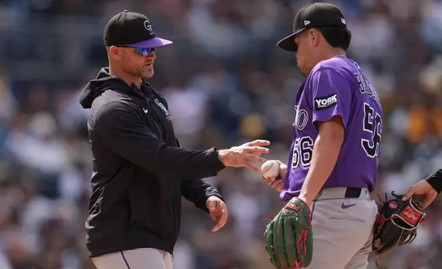 Colorado Rockies pitcher Valente Bellozo (56) hands the ball to manager Warren Schaeffer as he exits during the seventh inning of a baseball game against the San Diego Padres Sunday, April 12, 2026, in San Diego. (AP Photo/Gregory Bull)