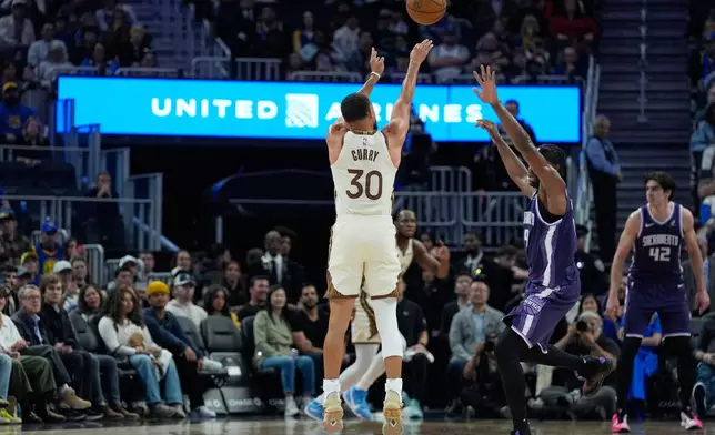 Golden State Warriors guard Stephen Curry (30) shoots a 3-point basket over Sacramento Kings forward Precious Achiuwa (9) during the first half of an NBA basketball game, Tuesday, April 7, 2026, in San Francisco. (AP Photo/Godofredo A. Vásquez)