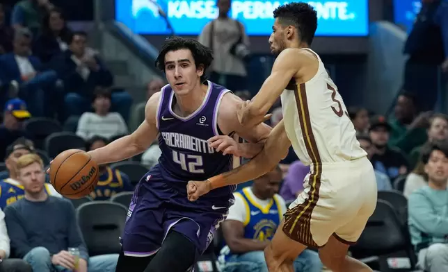 Sacramento Kings center Maxime Raynaud, left, moves the ball while defended by Golden State Warriors forward Malevy Leons during the first half of an NBA basketball game, Tuesday, April 7, 2026, in San Francisco. (AP Photo/Godofredo A. Vásquez)
