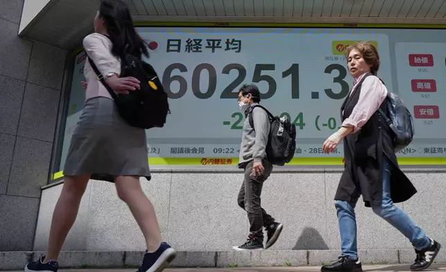 People past an electronic stock board showing Japan's Nikkei index at a securities firm Tuesday, April 28, 2026, in Tokyo. (AP Photo/Eugene Hoshiko)