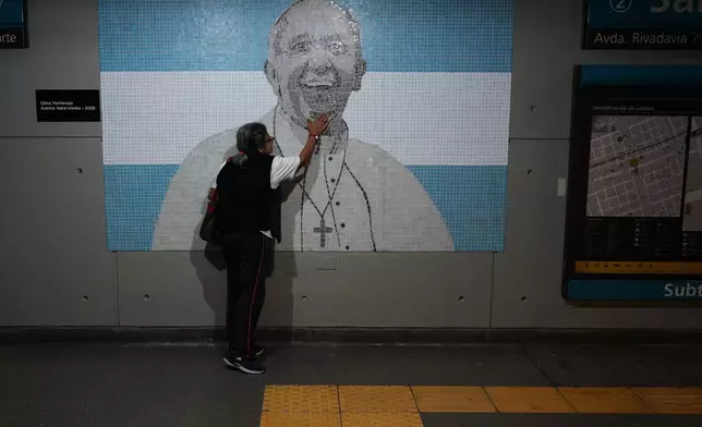 A commuter touches a mosaic of the late Pope Francis in a subway station on the one-year anniversary of his passing, in Buenos Aires, Argentina, Tuesday, April 21, 2026. (AP Photo/Rodrigo Abd)