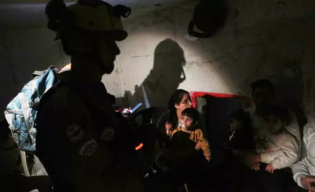 Israel's rescue teams and residents take shelter as sirens sounds next to a site struck by an Iranian missile in Bnei Brak, Wednesday, April 1, 2026. (AP Photo/Oded Balilty)