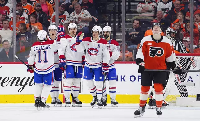 Montréal Canadiens' Jake Evans, center, high fives Brendan Gallagher (11) after Evans scored during the second period of an NHL hockey game against the Philadelphia Flyers, Tuesday, April 14, 2026, in Philadelphia. (AP Photo/Derik Hamilton)