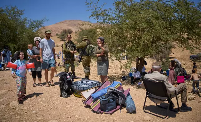 Soldiers stand guard while Israelis enjoy a day at a spring in Auja, in the Jordan Valley, during Israel's Independence Day on Wednesday, April 22, 2026, in the occupied West Bank. (AP Photo/Ohad Zwigenberg)