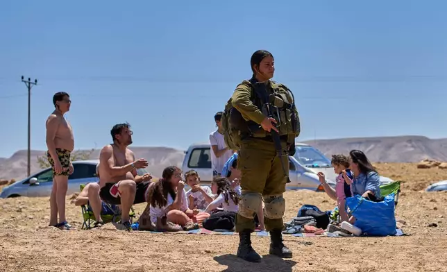 An Israeli soldier stands as Israeli settlers and others enjoy a day at a spring in the Jordan Valley during Israel's Independence Day, in Auja, in the occupied West Bank, Wednesday, April 22, 2026.(AP Photo/Ohad Zwigenberg)