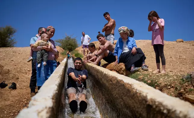 A man slides down into a spring as Israeli settlers and others enjoy a day in the Jordan Valley during Israel's Independence Day, in Auja, in the occupied West Bank, Wednesday, April 22, 2026.(AP Photo/Ohad Zwigenberg)
