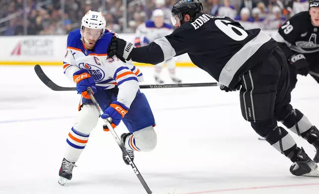 Edmonton Oilers center Connor McDavid, left, moves the puck against Los Angeles Kings defenseman Joel Edmundson, right, during the first period of an NHL hockey game Saturday, April 11, 2026, in Los Angeles. (AP Photo/Ryan Sun)