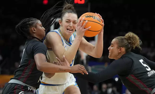 UCLA forward Angela Dugalic (32) drives against South Carolina guard Ta'Niya Latson, left, and South Carolina guard Tessa Johnson (5) during the second half of the women's National Championship Final Four NCAA college basketball tournament game, Sunday, April 5, 2026, in Phoenix. (AP Photo/Rick Scuteri)
