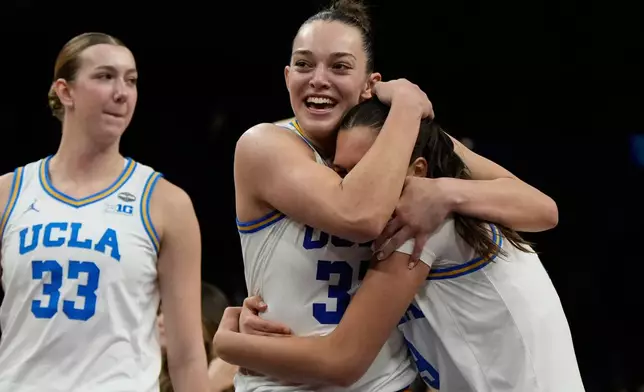 UCLA forward Angela Dugalic, second from left, embraces UCLA guard Lena Bilic (9) after defeating Texas in a women's NCAA college basketball tournament semifinal game at the Final Four, Friday, April 3, 2026, in Phoenix. (AP Photo/Ross D. Franklin)