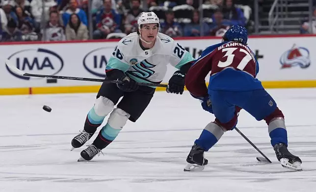 Seattle Kraken defenseman Joshua Mahura, left, drives past Colorado Avalanche defenseman Nick Blankenburg in the second period of an NHL hockey game Thursday, April 16, 2026, in Denver. (AP Photo/David Zalubowski)