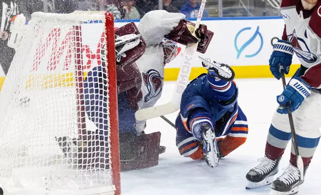 Colorado Avalanche goalie Scott Wedgewood (41) is knocked over by Edmonton Oilers' Kasperi Kapanen (42) during overtime NHL action, in Edmonton, Alberta, on Monday, April 13, 2026. (Jason Franson/The Canadian Press via AP)