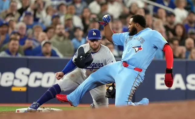 Los Angeles Dodgers third baseman Max Muncy (13) tags out Toronto Blue Jays Vladimir Guerrero Jr. (27) during the sixth inning of a baseball game in Toronto, Wednesday, April 8, 2026. (Nathan Denette/The Canadian Press via AP)