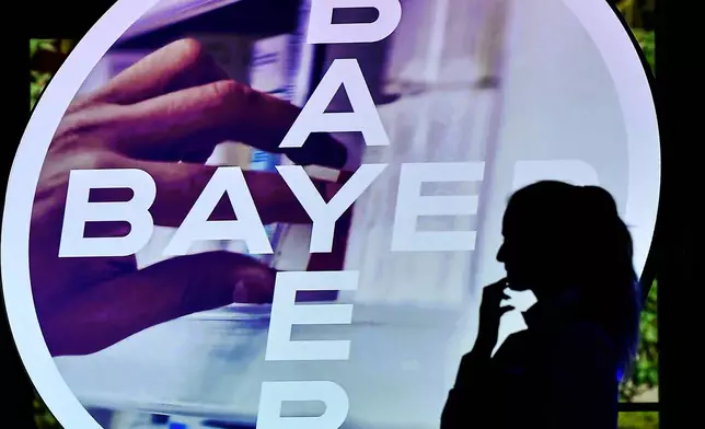 FILE - A woman walks in front of a logo of Bayer AG at the Financial News Conference, in Leverkusen, Germany, Feb. 27, 2020. (AP Photo/Martin Meissner, File)