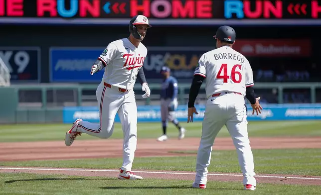 Minnesota Twins' Matt Wallner celebrates with third base coach Ramon Borrego (46) after hitting a solo home run during the second inning of a baseball game against the Tampa Bay Rays, Sunday, April 5, 2026, in Minneapolis. (AP Photo/Bailey Hillesheim)