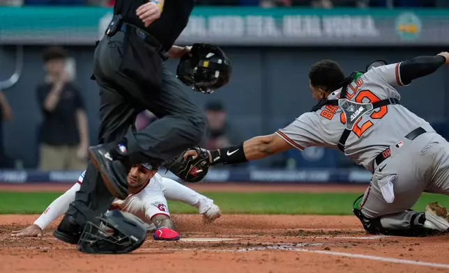 Cleveland Guardians' Brayan Rocchio, left, scores under the tag of Baltimore Orioles catcher Samuel Basallo (29) on a single hit by Steven Kwan in the fifth inning of a baseball game in Cleveland, Thursday, April 16, 2026. (AP Photo/Sue Ogrocki)