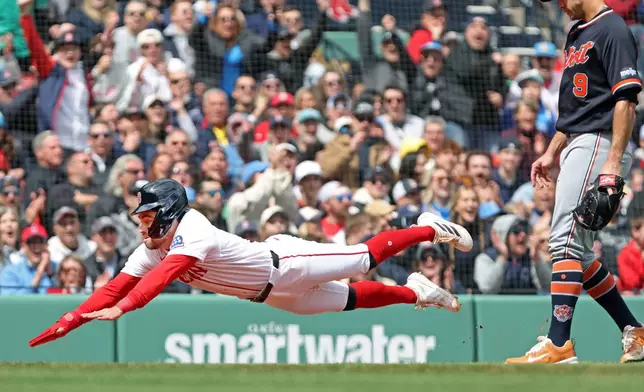 Boston Red Sox' Caleb Durbin dives headfirst into home plate as he scores on a second inning throwing error by Detriot Tigers' pitcher Jack Flaherrty, right, during a baseball game Monday, April 20, 2026 in Boston. (AP Photo/Jim Davis)