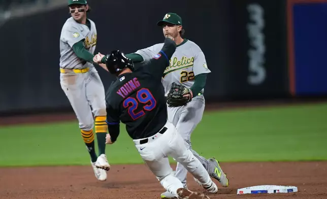 Athletics' Jeff McNeil (22) throws out New York Mets' Luis Robert Jr. at first base after forcing out New York Mets' Jared Young (29) for a double play during the sixth inning of a baseball game Friday, April 10, 2026, in New York. (AP Photo/Frank Franklin II)